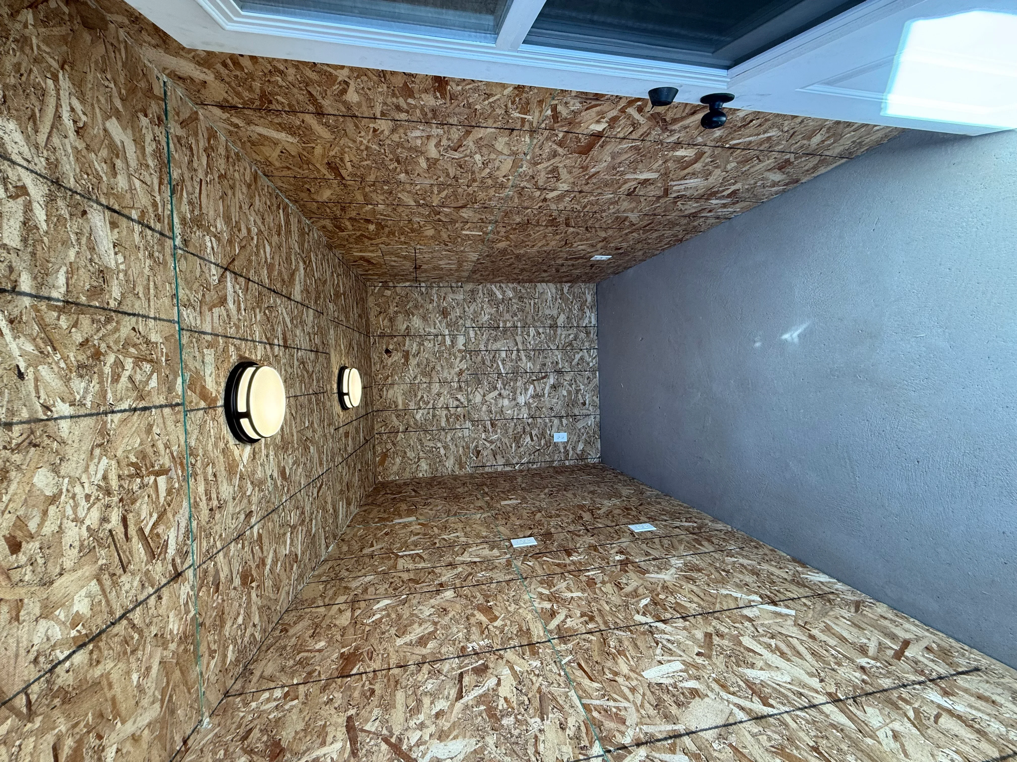 Metal building interior with OSB walls, electrical conduit, drywall, and recessed lighting fixtures
