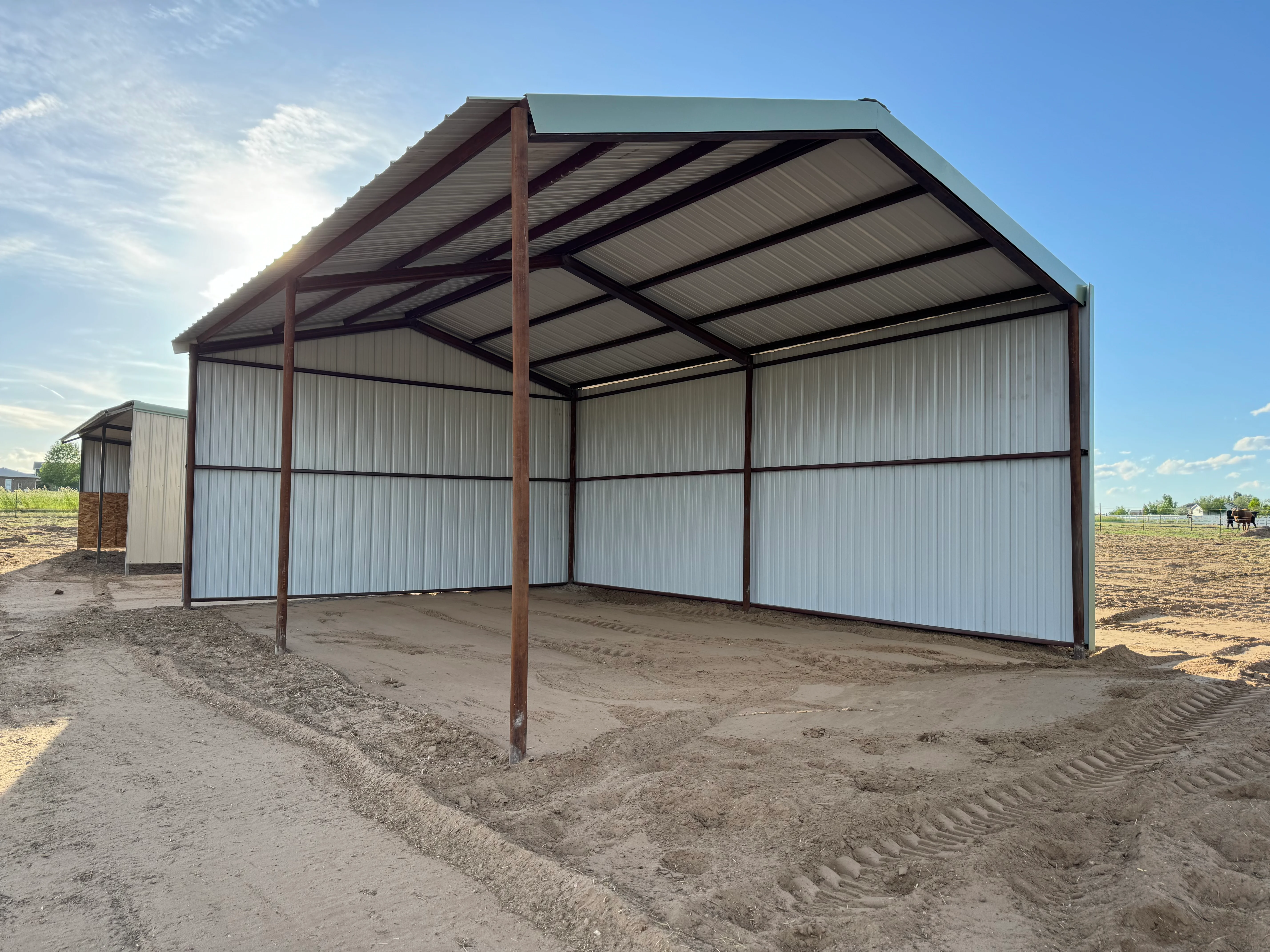 Metal carport with brown steel frame and white corrugated panels in rural setting