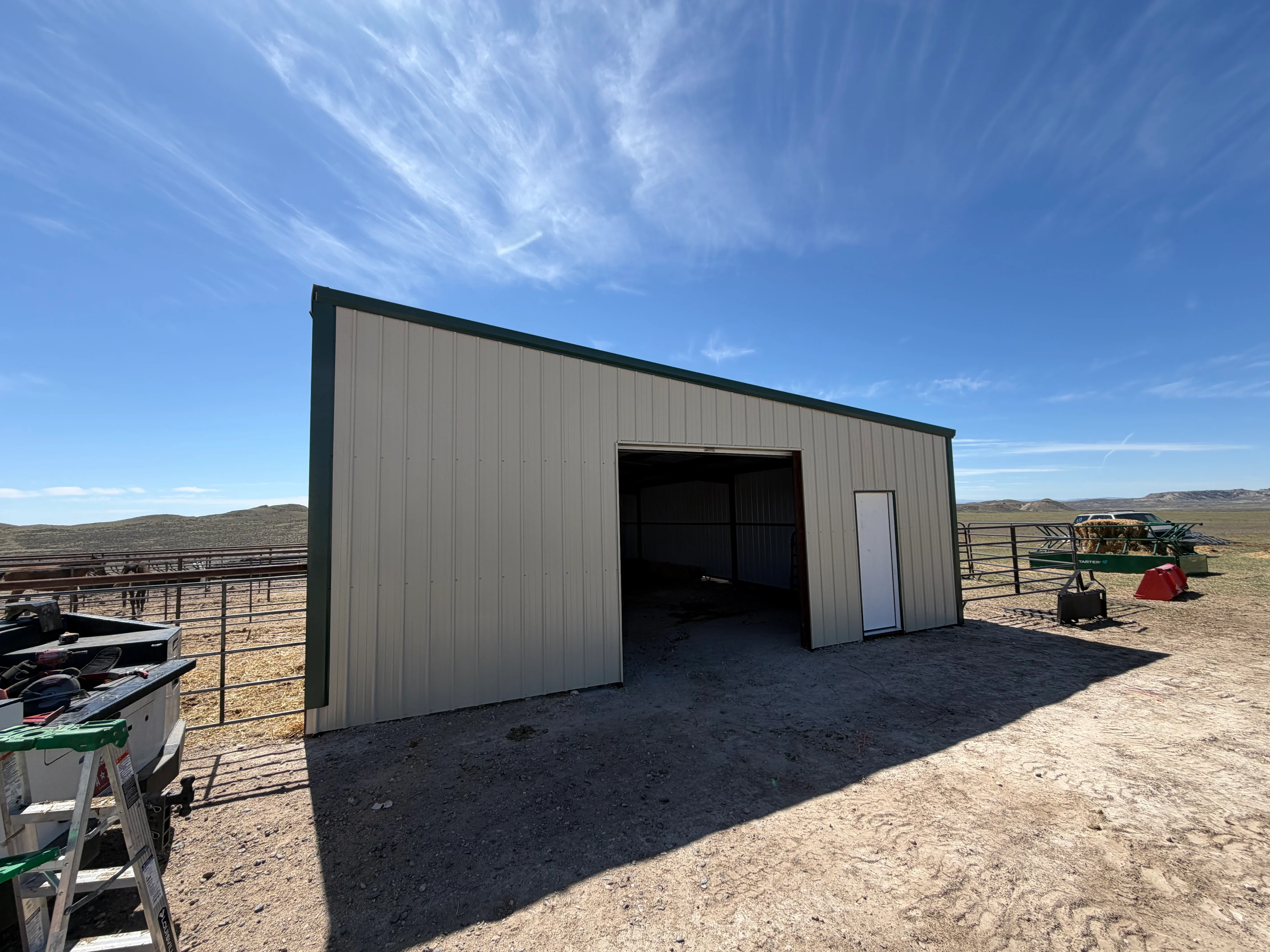 Metal building with corrugated steel panels, roll-up door, and personnel entry on rural property
