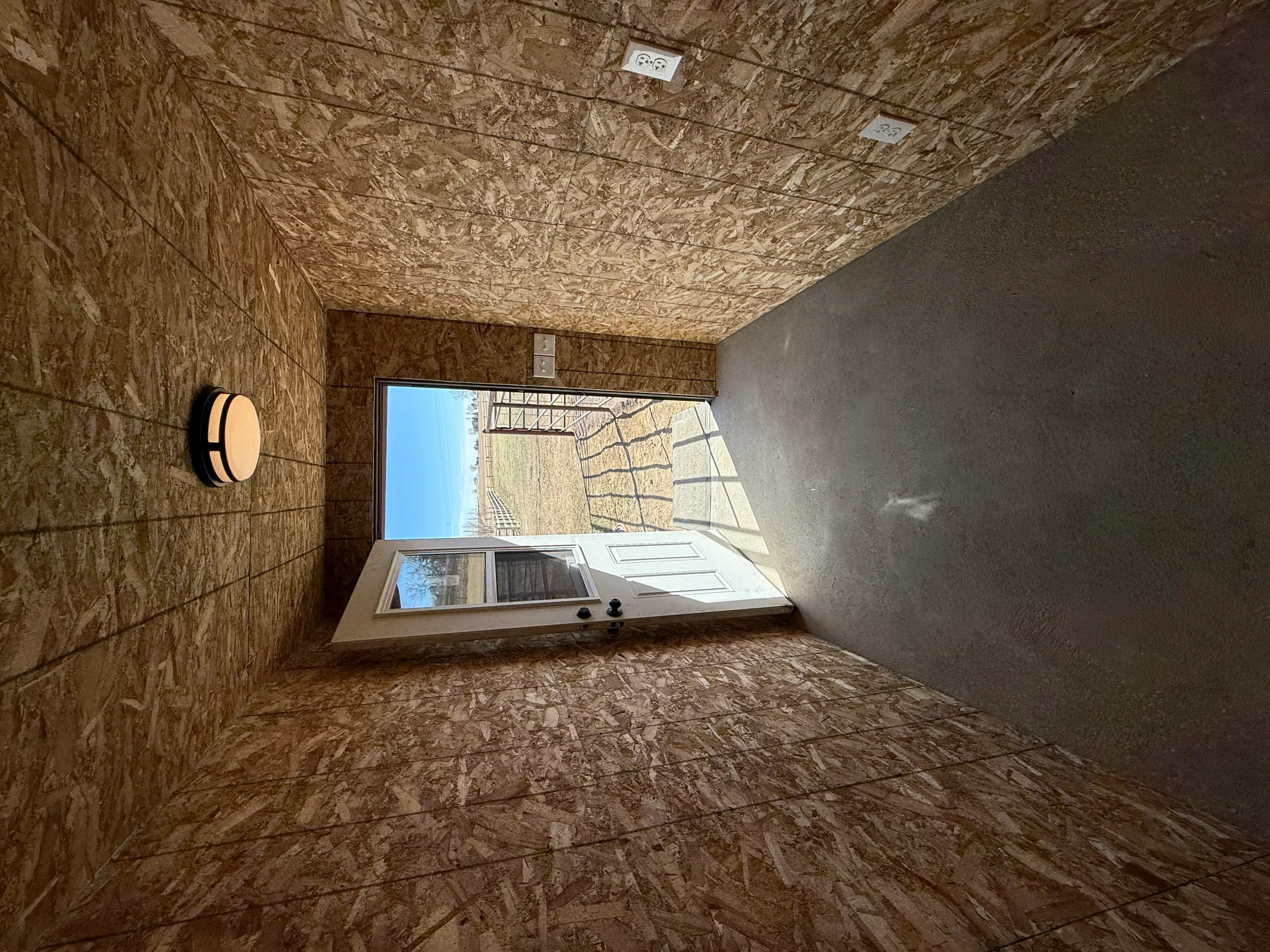 Metal building interior with OSB wall and ceiling sheathing, electrical wiring, and window frame installation