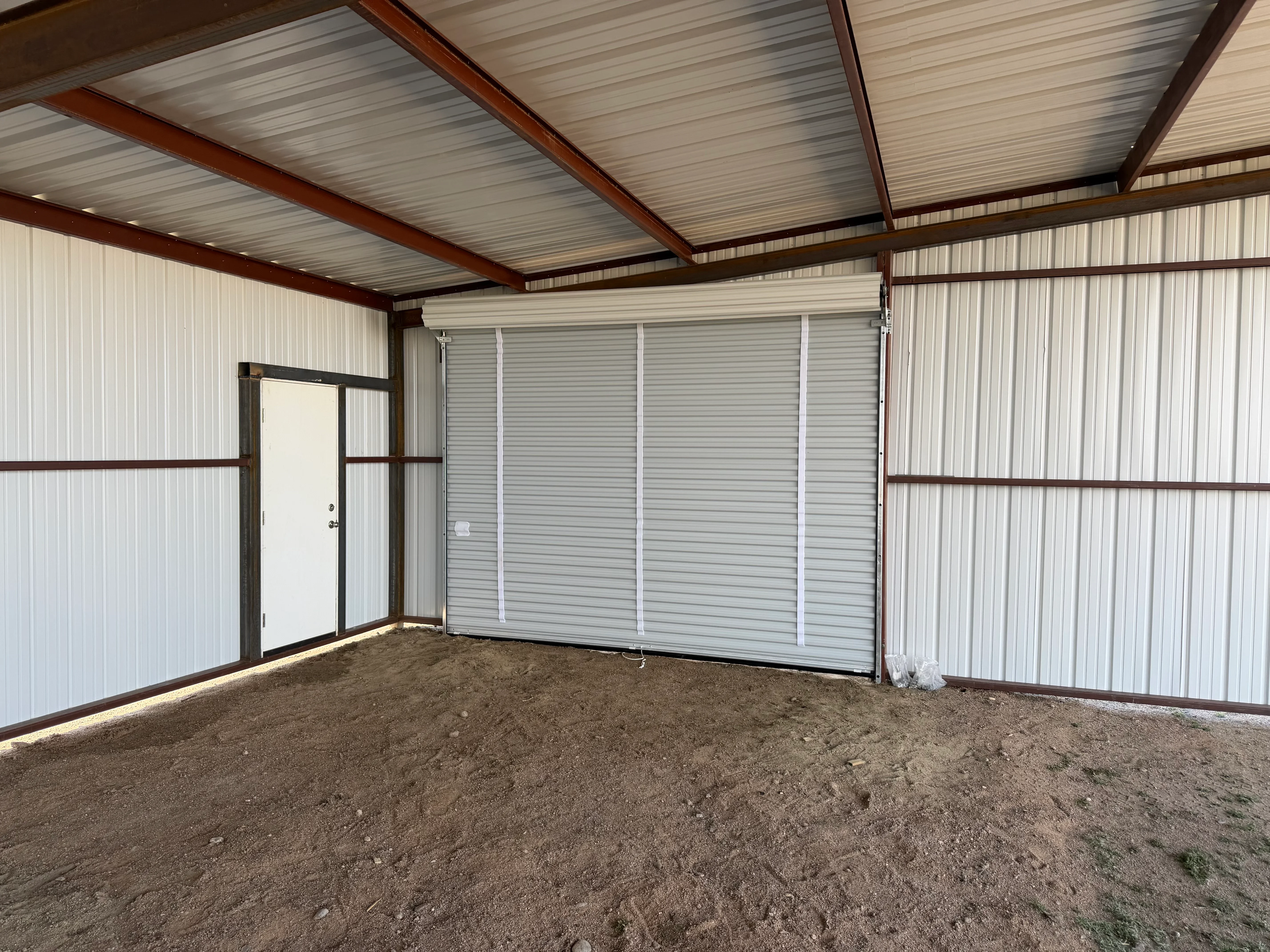 Metal loafing shed with white corrugated siding, steel frame, and sliding doors