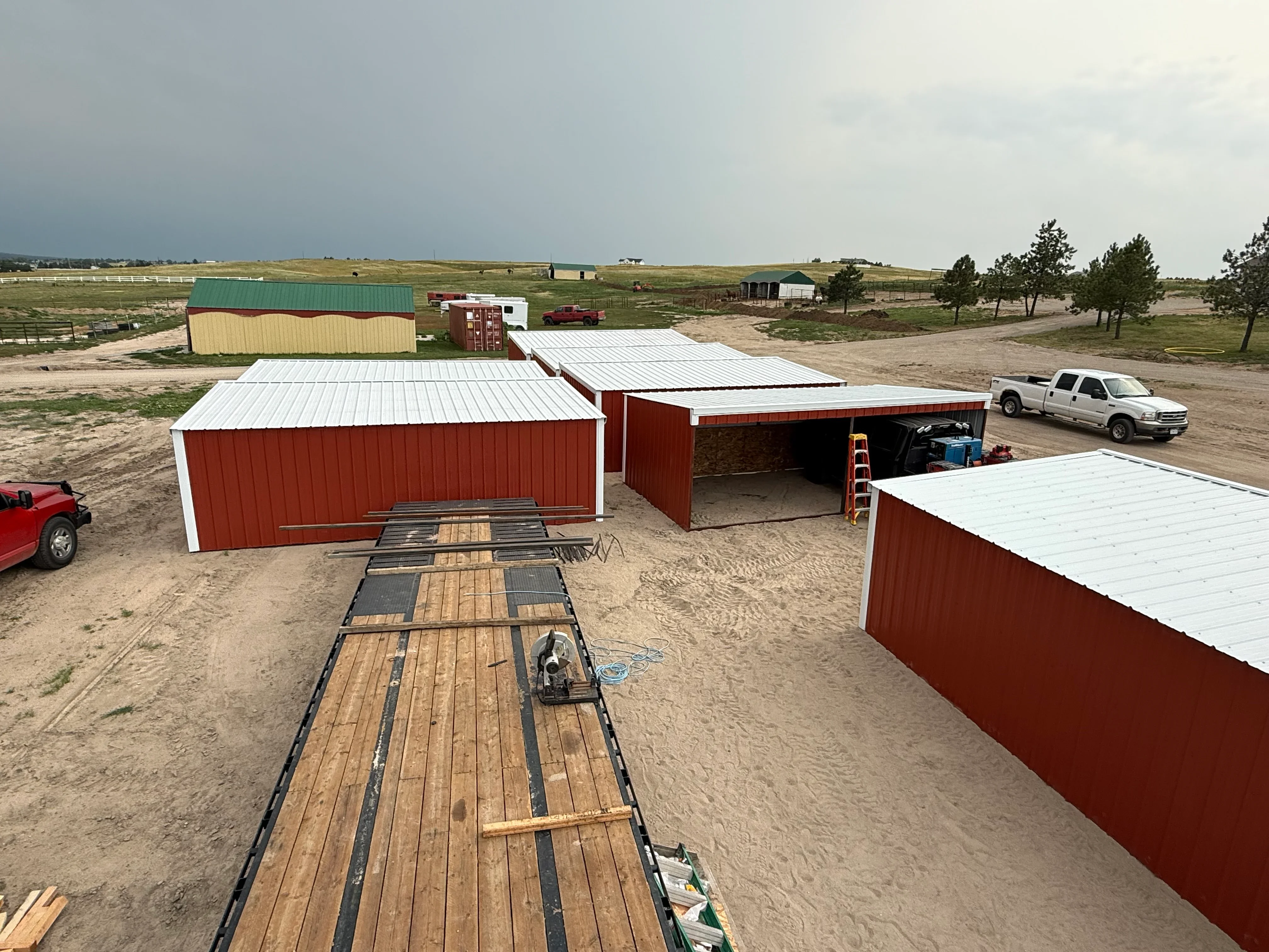 Red corrugated metal buildings with white standing seam metal roofs on prepared site