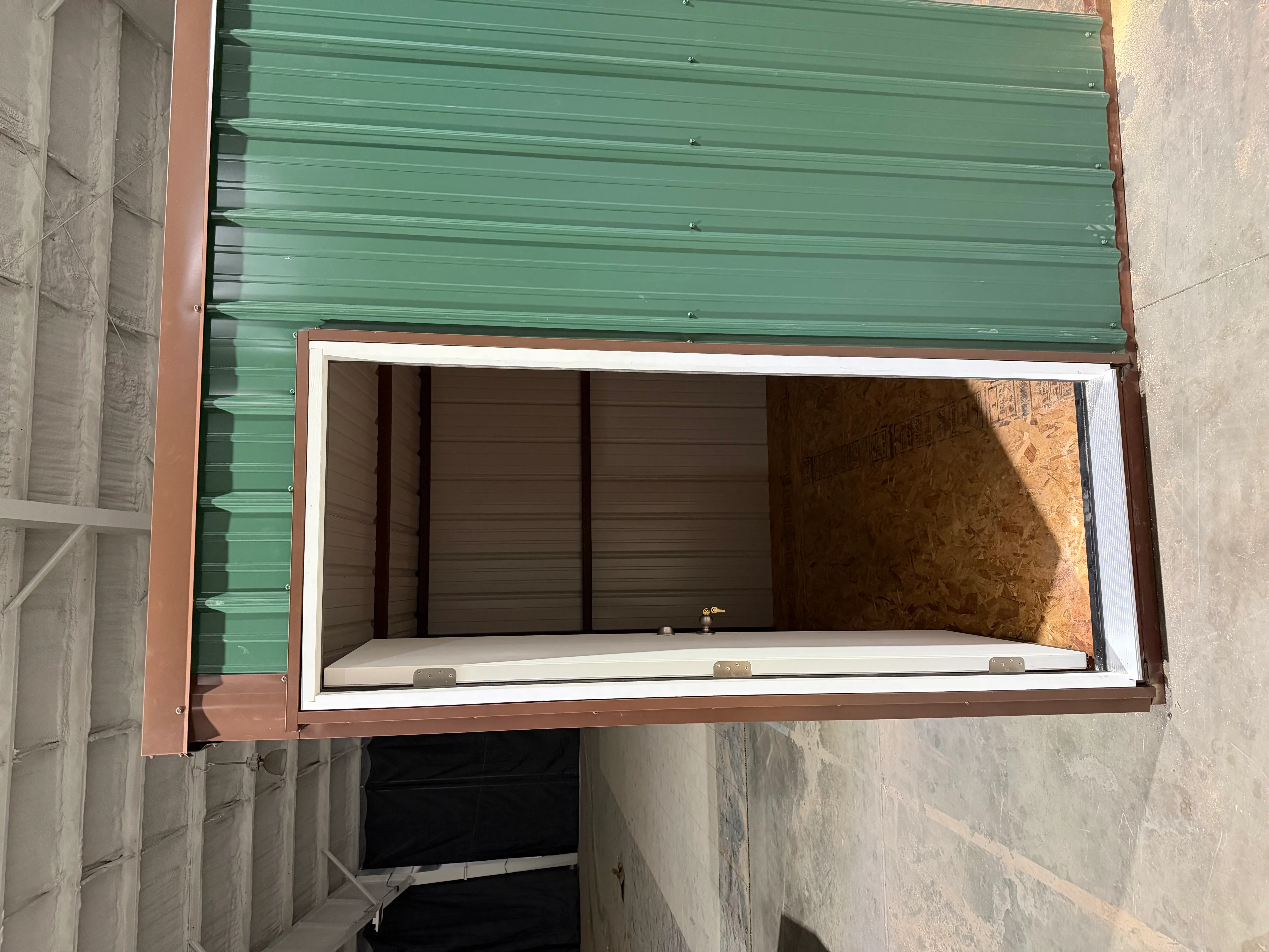 Green corrugated metal roof and dark metal wall panels on completed metal building structure