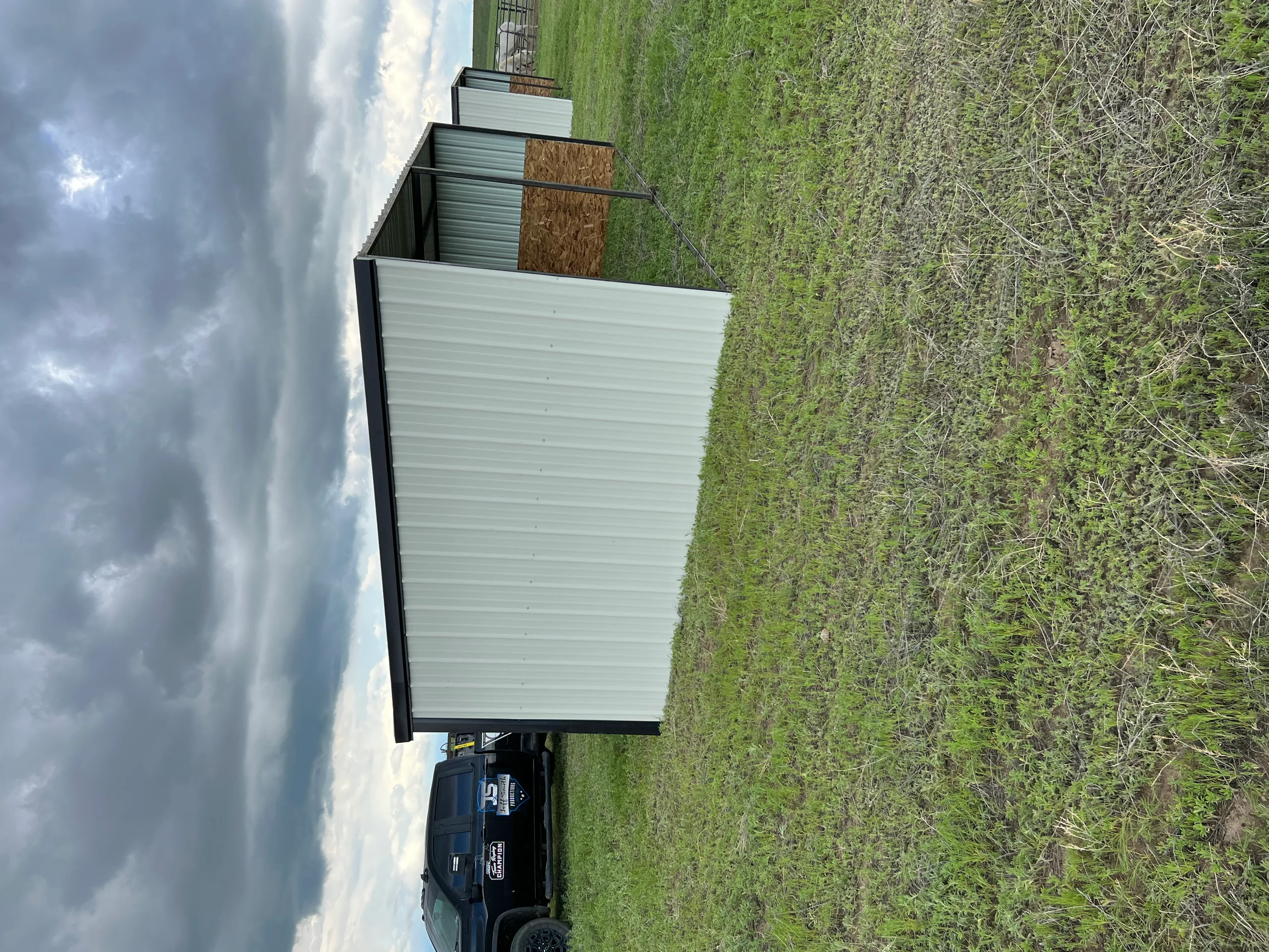 Metal building with corrugated siding, black trim, and peaked roof under construction