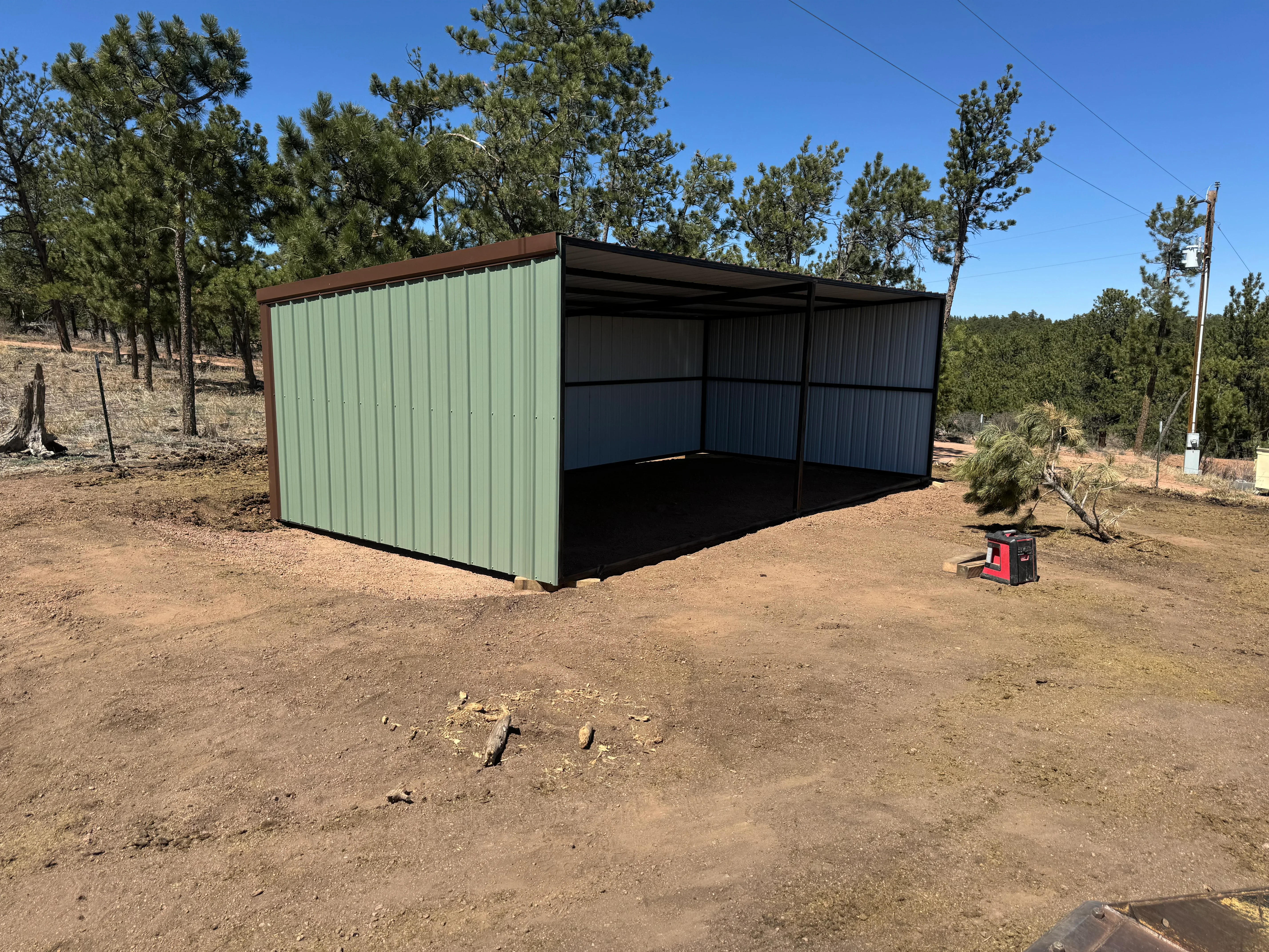 Corrugated metal shelter with sage green and black panels, open-sided design, steel frame construction