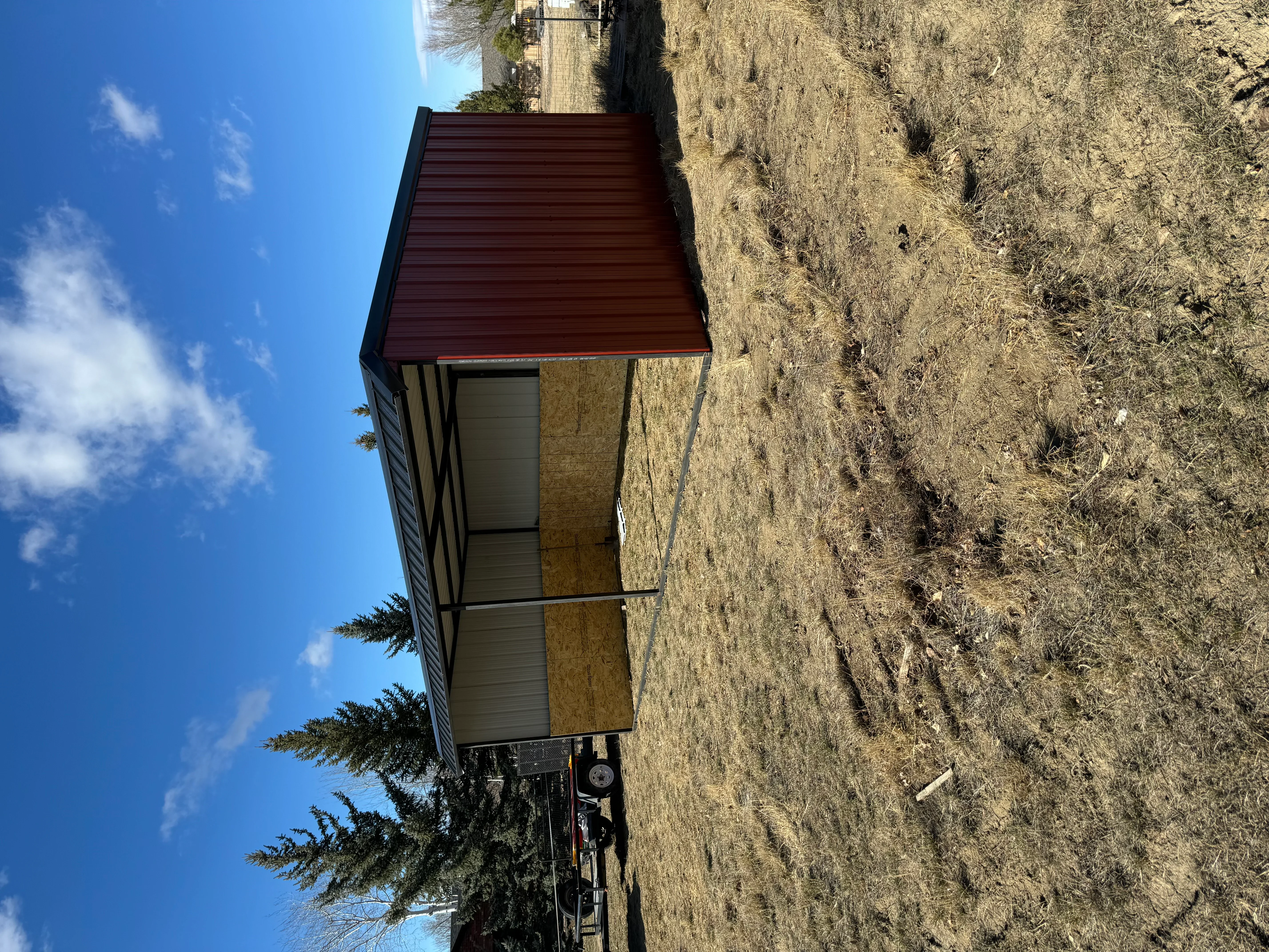 Metal building with corrugated red roof and tan metal siding on concrete foundation