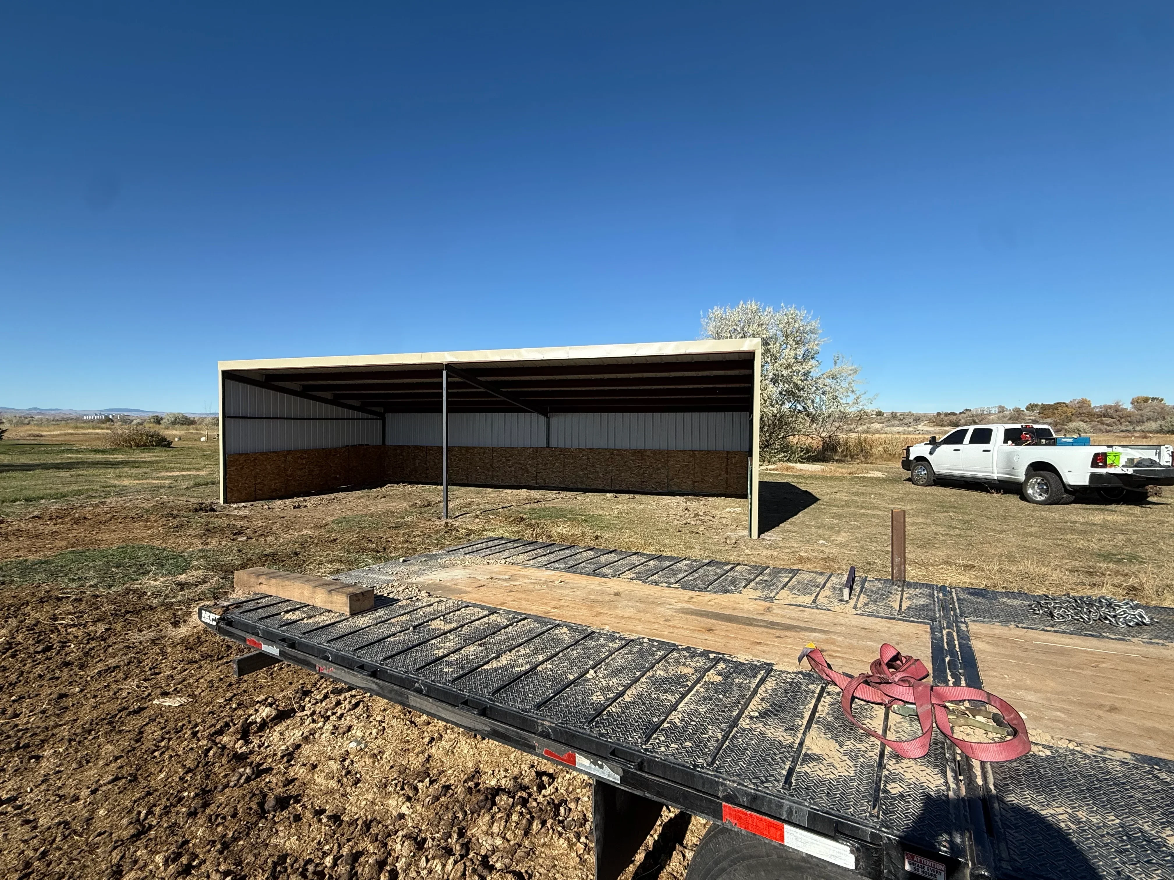 Metal frame shelter with corrugated steel panels and concrete foundation on rural property
