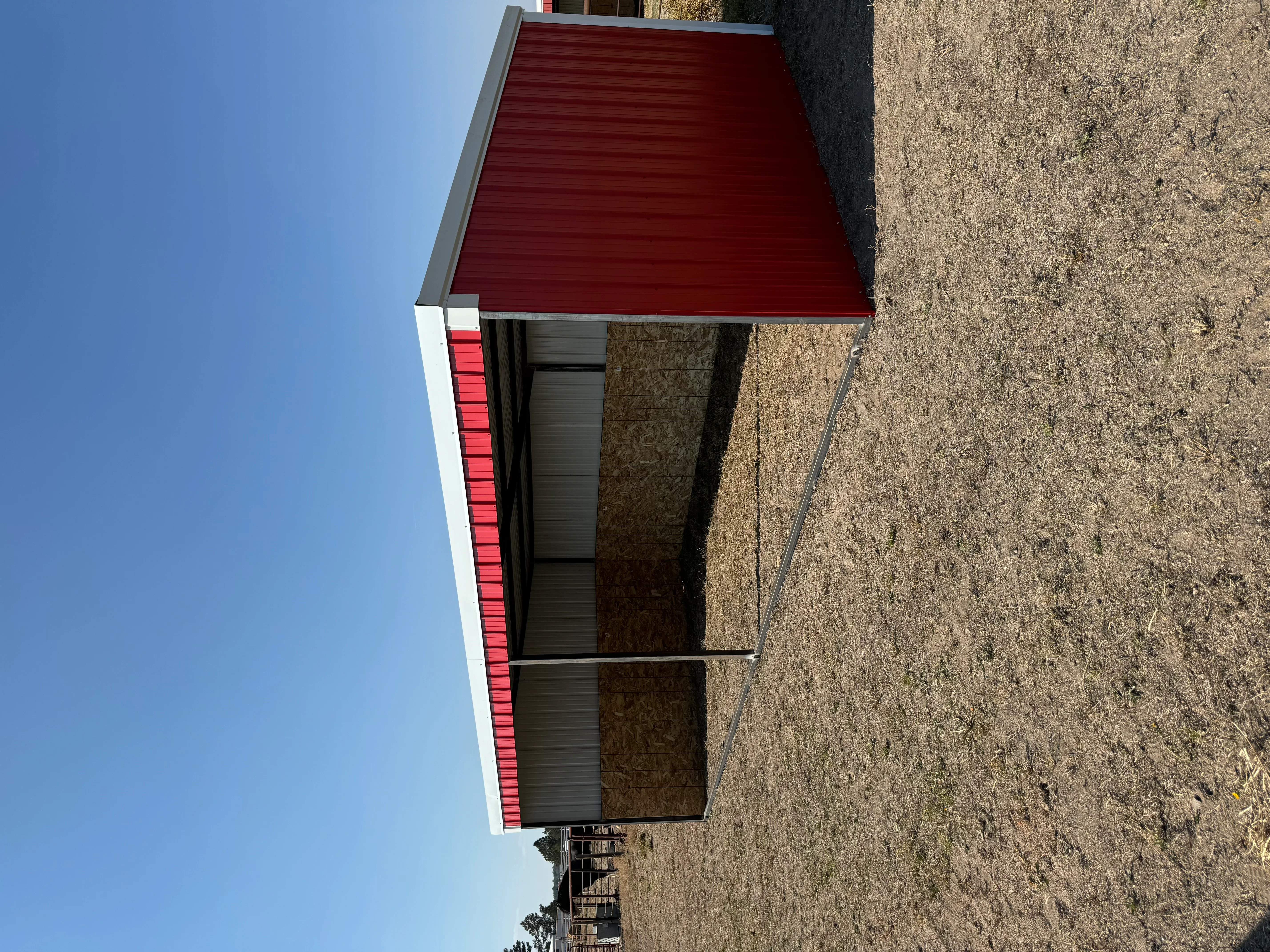 Red corrugated metal roof with gray trim on metal frame building with dark metal siding