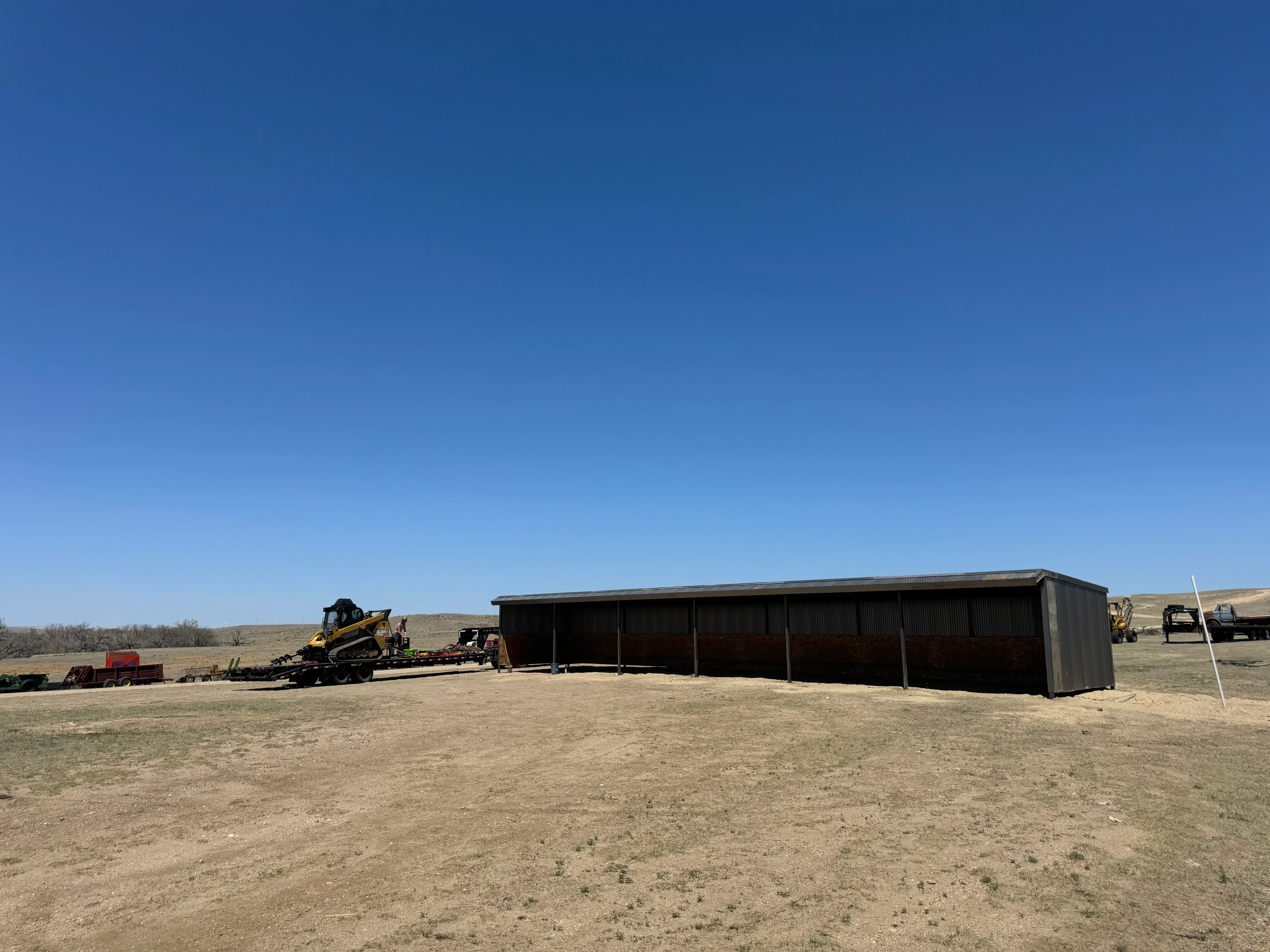 Metal building with corrugated steel siding and open bays on prepared ground site