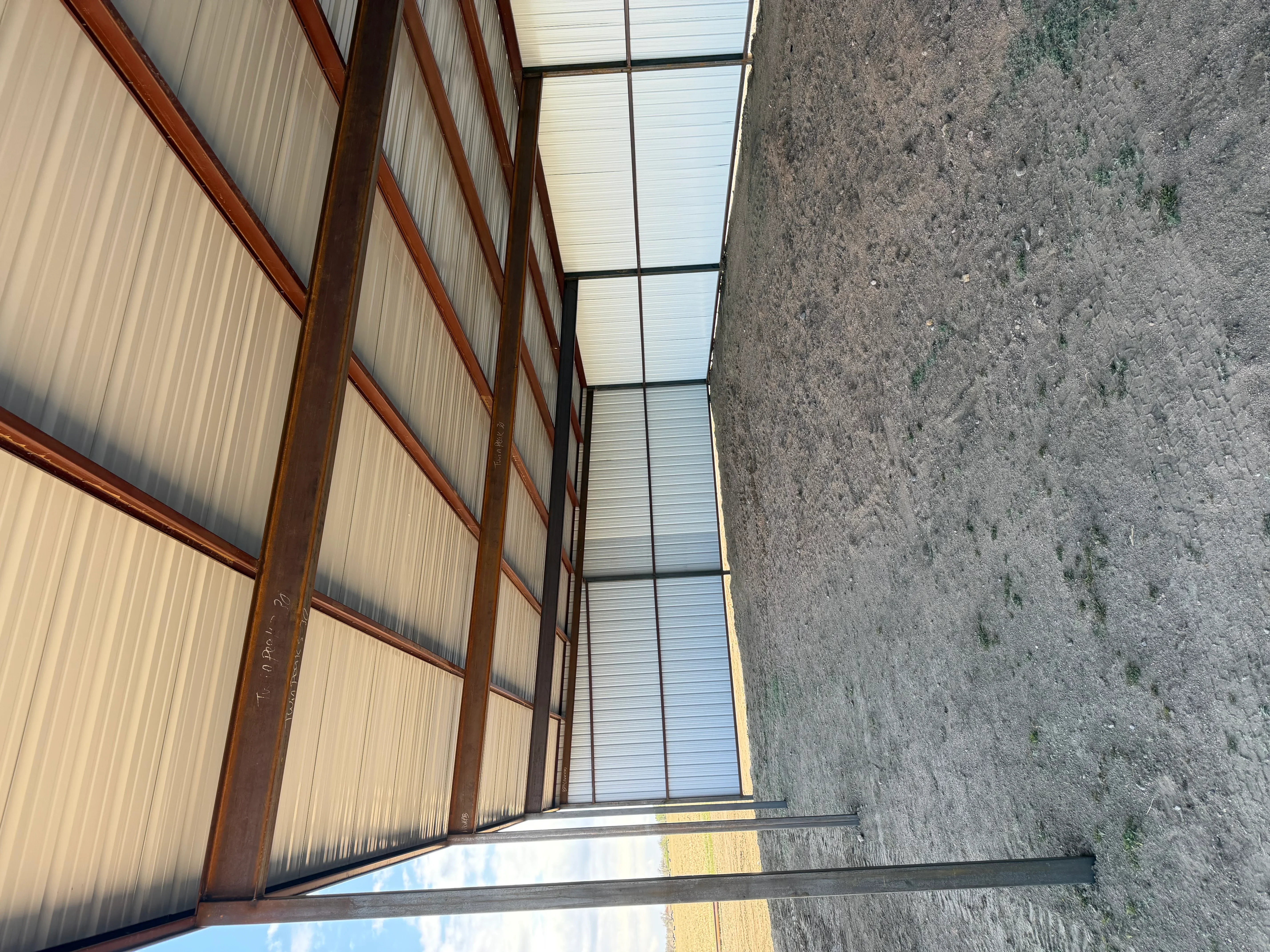 Metal building frame with steel I-beams and polycarbonate roof panels under construction