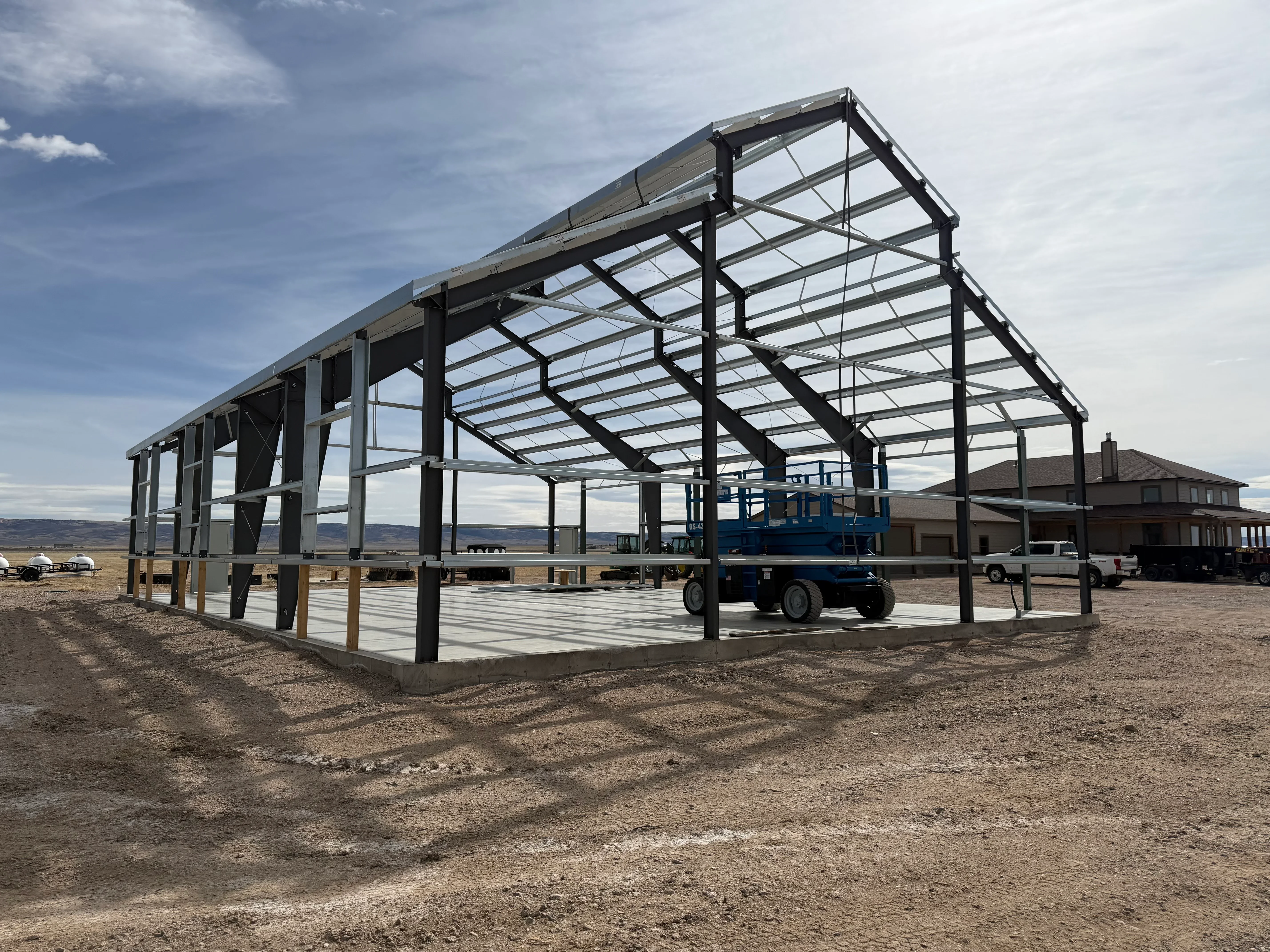 Steel frame agricultural building with corrugated metal roof and wall panels under construction
