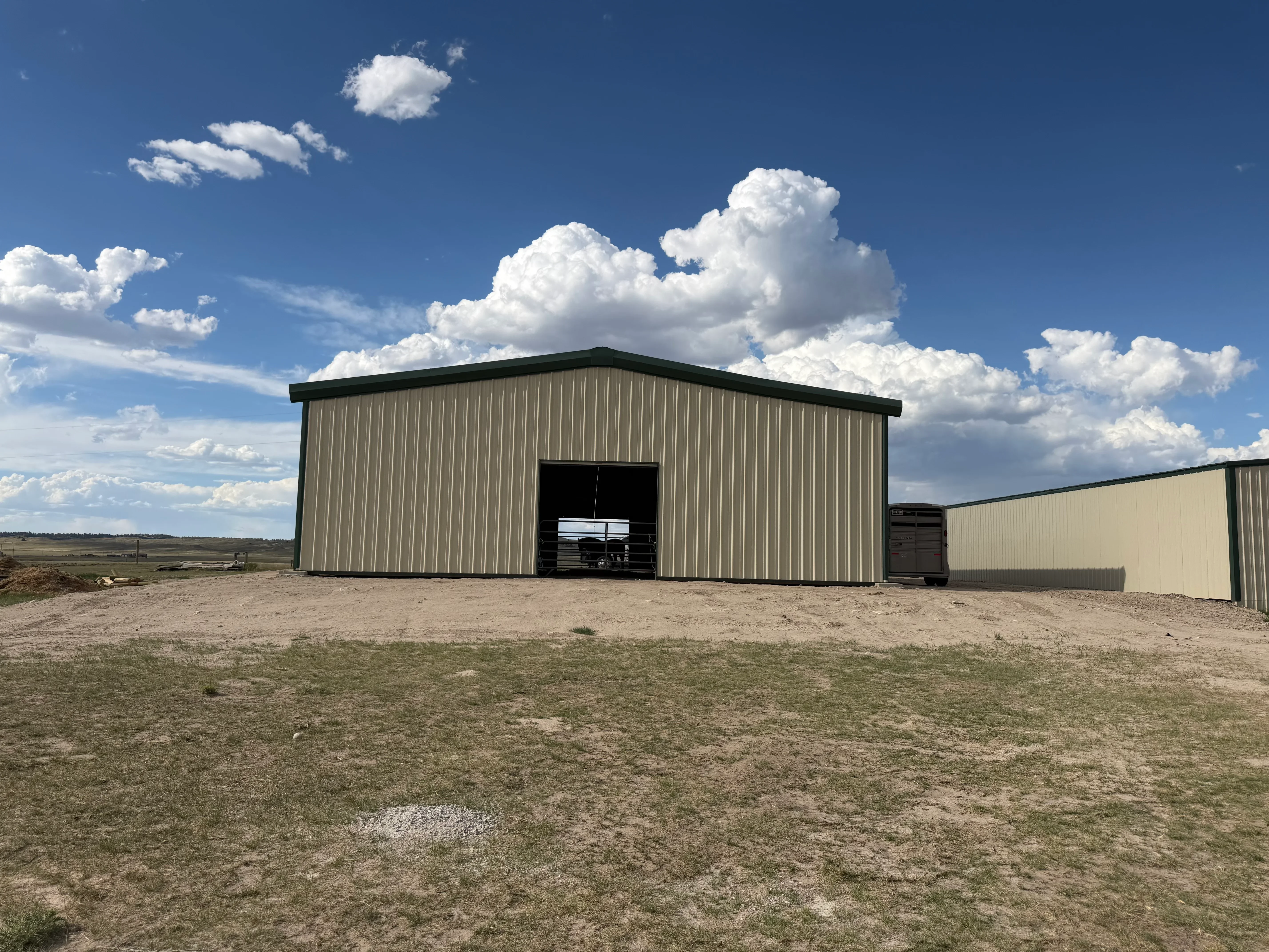 Metal building with corrugated steel siding, dark trim roof, and overhead door on gravel foundation