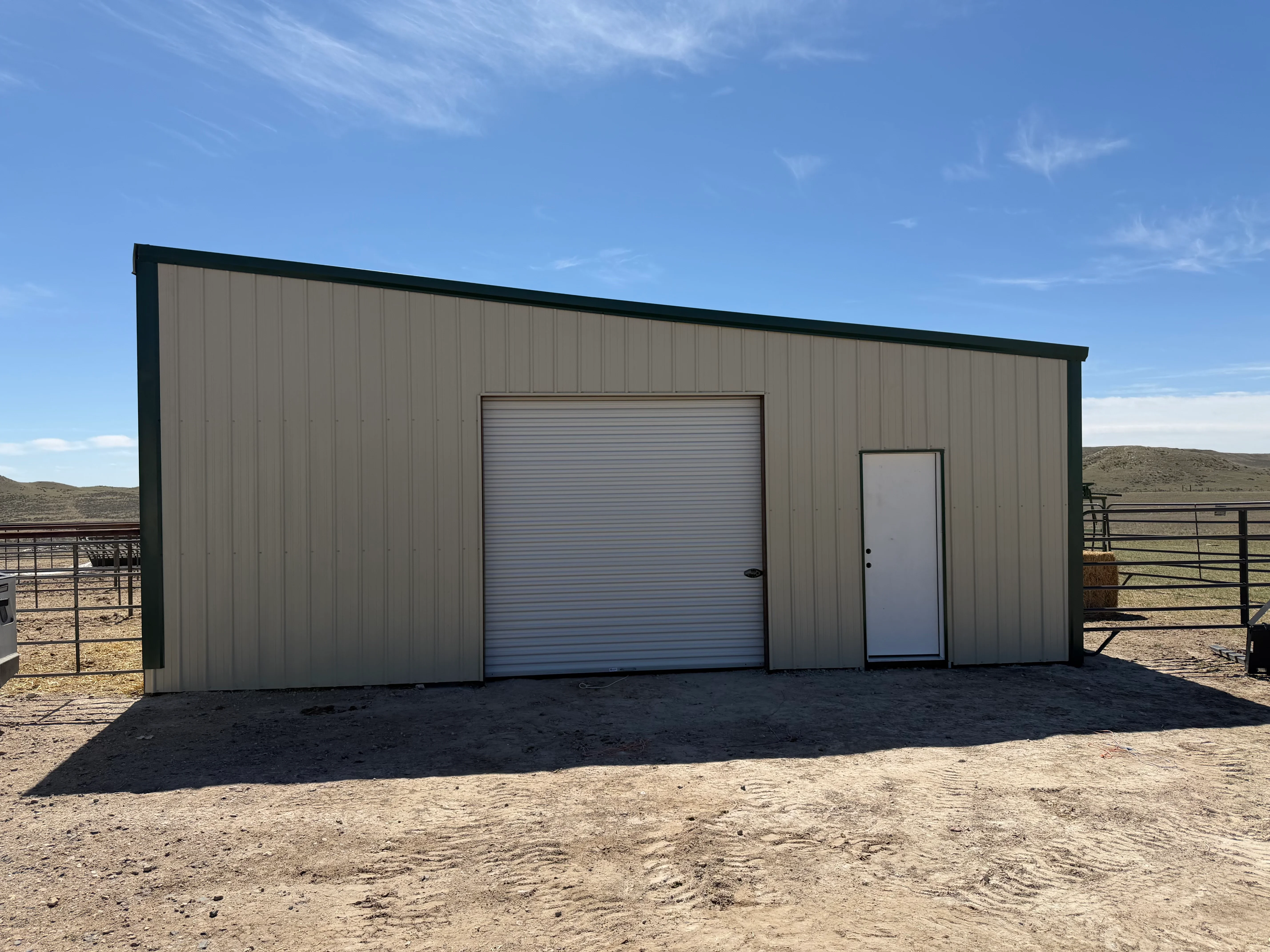 Metal garage with vertical corrugated steel siding, rollup door, and entry door